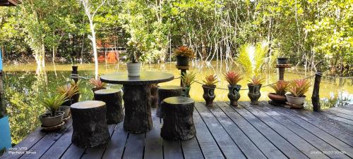 a wooden deck with a table and some potted plants at TA YAI HOMESTAY (ตา ยาย โฮมสเตย์) in Ko Kood