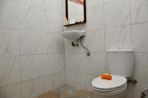 een badkamer met een wit toilet en een wastafel bij Warung ombak homestay in Amed