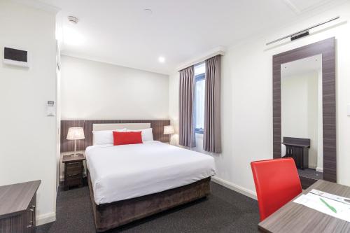a hotel room with a bed, chair, and nightstand at ibis Styles Kingsgate Hotel in Melbourne