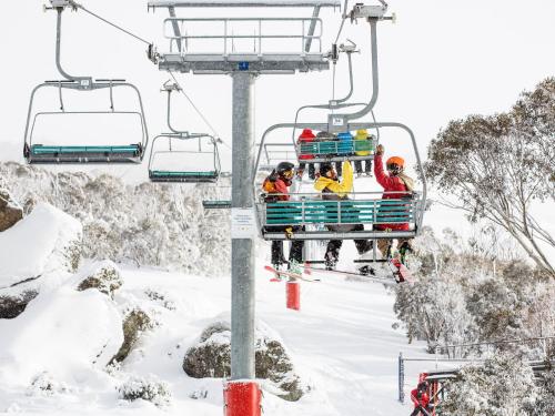 a group of people riding a ski lift in the snow at Snowbird 1 - Charming 2BR Townhouse l Lake Views l Air-Con l Off-Street Parking in Jindabyne