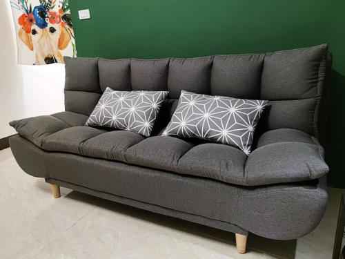 a gray couch with three pillows on it at Lin's B&B in Pingtung City