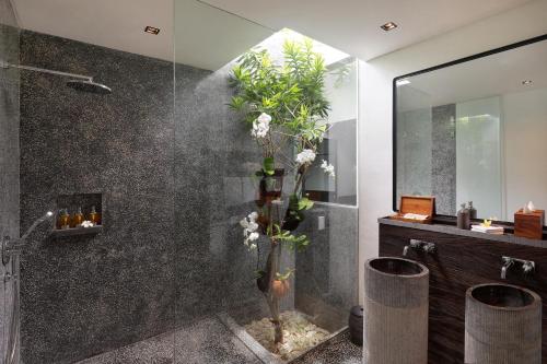 a bathroom with a shower with a vase of flowers at MAUA Nusa Penida Bali in Nusa Penida