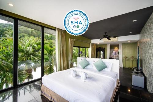 a bedroom with a large white bed with a large window at See Sea Villa Phuket SHA in Patong Beach