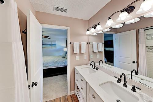 baño con 2 lavabos y espejo grande en Trade Wind Cabana en Saint Augustine