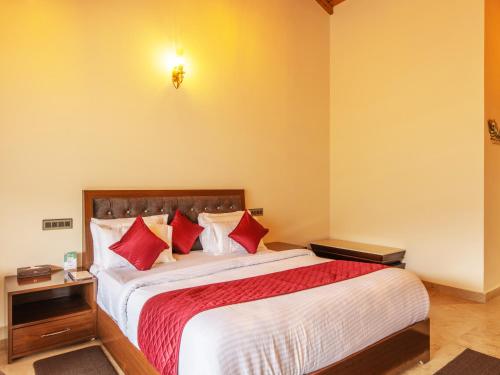 a bedroom with a large bed with red pillows at Captains Paradise Luxury Resort at Mukteshwar Hill Station in Mukteswar