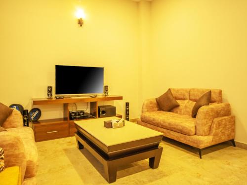 a living room with two chairs and a flat screen tv at Captains Paradise Luxury Resort at Mukteshwar Hill Station in Mukteswar