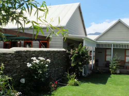 a house with a stone wall and a fence at Doorways in Barrydale