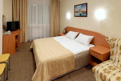 Habitación de hotel con cama y silla en Tchernomorye Resort, en Nébug