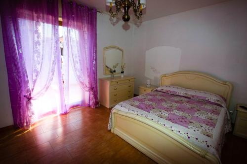 1 dormitorio con cama, cortinas rosas y espejo en Casa Vacanze San Lorenzo, en Agerola