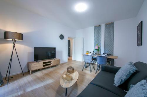 Boutique Apartments - Happy Rentals في لوغانو: غرفة معيشة مع أريكة وتلفزيون وطاولة