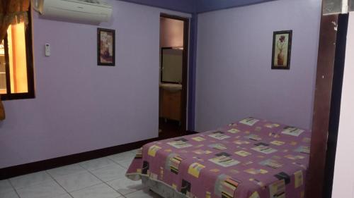 ein Schlafzimmer mit einem Bett und einer lila Wand in der Unterkunft jCONFARM in Calamba