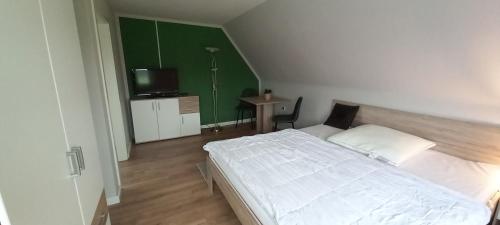 ein Schlafzimmer mit einem weißen Bett und einer grünen Wand in der Unterkunft zum Kranichblick in Glinstedt