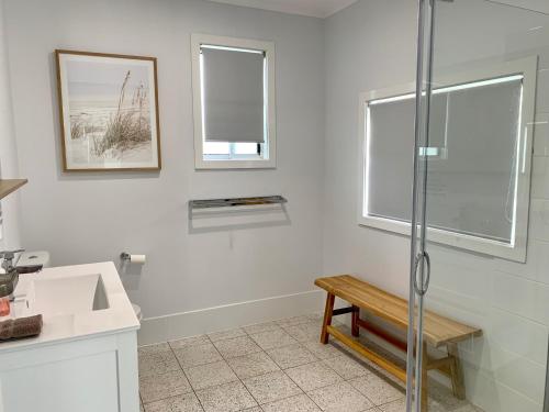 a bathroom with a shower and a bench and windows at Salty Dog in Emu Bay