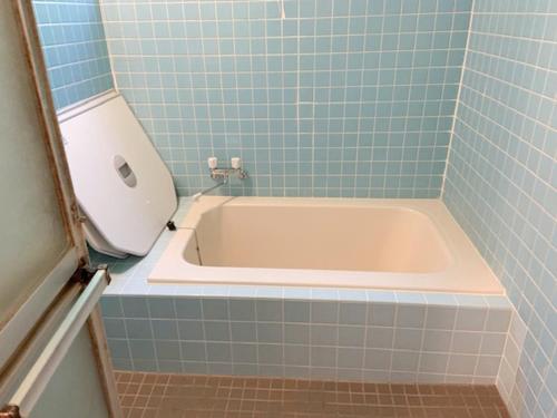 uma banheira na casa de banho com azulejos azuis em 五岳庵 em Shinano