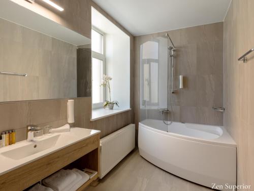 La salle de bains est pourvue d'une baignoire blanche, d'un lavabo et d'une baignoire. dans l'établissement Kreutzwald Hotel Tallinn, à Tallinn