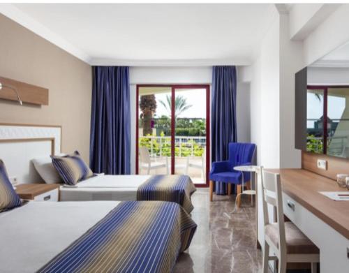 Habitación de hotel con 2 camas y escritorio en Galeri Resort Hotel - Ultra All Inclusive, en Okurcalar