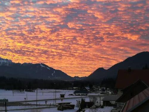 a sunset over a town with snow and mountains at Žbogar in Rateče