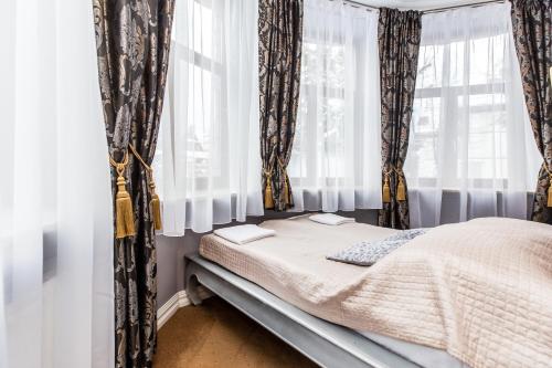 a bed in a room with curtains and a window at Willa Excelsior in Zakopane