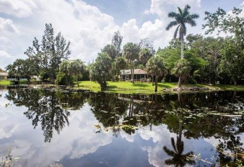 a house with a palm tree reflected in a pond at Unwind Island in West Palm Beach