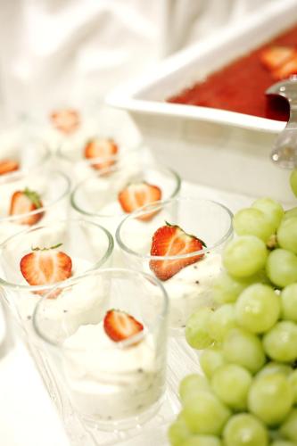 a group of cups with strawberries and whipped cream next to green grapes at H+ Hotel Stade Herzog Widukind in Stade