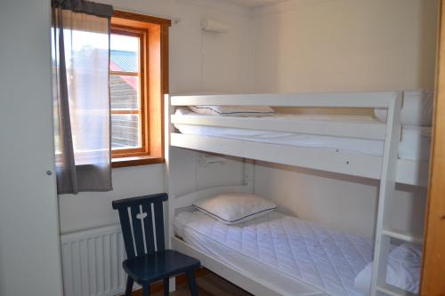 a bedroom with bunk beds with a chair and a window at First Camp Enåbadet - Rättvik in Rättvik