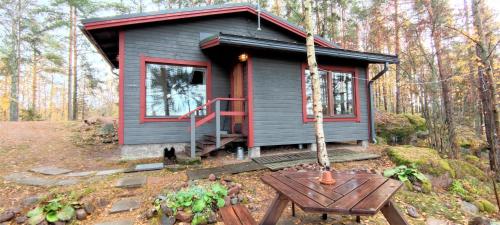 a tiny house in the woods with a table at Pyhtään Vuokramökit in Tuuski