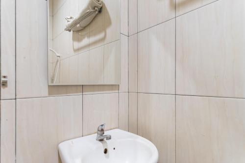 a white bathroom with a sink and a mirror at Vandolia Guest House Medan RedPartner in Medan