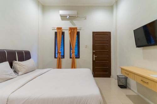 1 dormitorio con 1 cama y TV de pantalla plana en Vandolia Guest House Mitra RedDoorz, en Medan