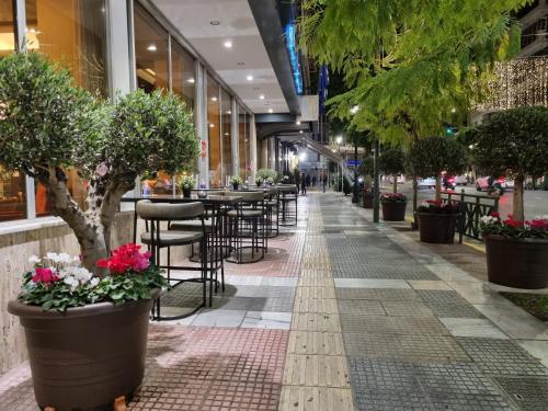 a street with tables and chairs and potted plants at Savoy Hotel in Piraeus
