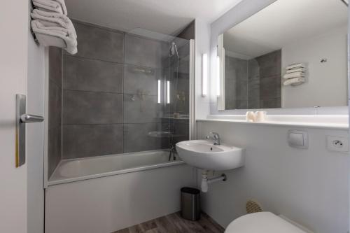 een badkamer met een douche, een wastafel en een toilet bij Le 2 By Hotel Akena - La Ferté Bernard in La Ferté-Bernard