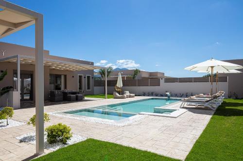 a backyard with a swimming pool and an umbrella at Koin Villa Sunset, With Heated Pool & Whirlpool, By ThinkVilla in Perama