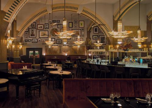 a restaurant with tables and chairs and a bar at Clayton Hotel Amsterdam American in Amsterdam