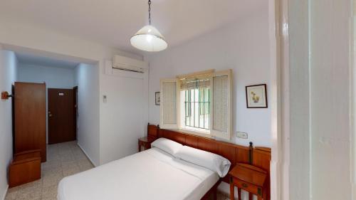 a bedroom with a white bed and a window at Pension Gala in Seville