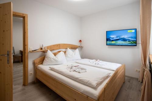 a bedroom with a wooden bed with a tv on the wall at Apartmenthaus HAUS Gipfelglück Apartment DOCHSTOA in Haus im Ennstal