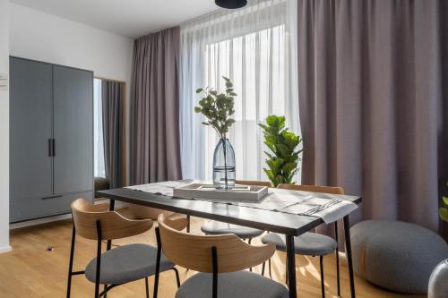 a dining room table with chairs and a vase with flowers at Limehome Potsdam Annemarie-Wolff-Platz in Potsdam