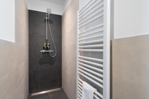 a bathroom with a shower with black tiles at limehome Potsdam Annemarie-Wolff-Platz in Potsdam