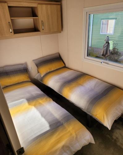 two beds in a small room with a window at Lovely Static Caravan at Billing Aquadrome in Great Billing