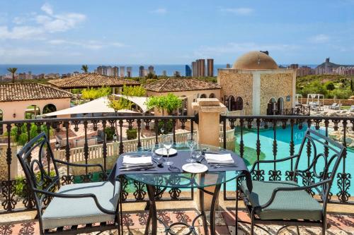 a table and chairs on a balcony with a pool at Melia Villaitana in Benidorm