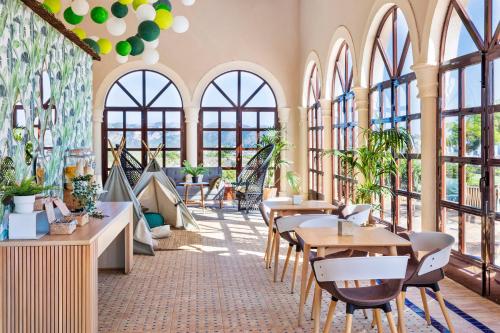 a restaurant with tables and chairs and windows at Melia Villaitana in Benidorm