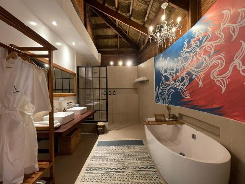 a bathroom with two sinks and a tub and a painting at Mua Tala Hotel El Nido in El Nido