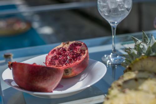 einem Granatapfel auf einem Teller auf einem Tisch mit einem Weinglas in der Unterkunft Ayia Napa Ionion Seaside Villa in Ayia Napa