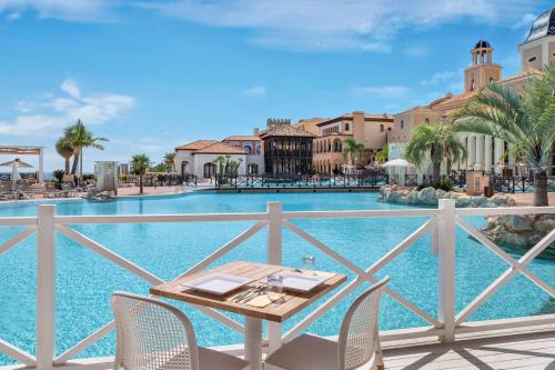 a table and chairs on a balcony with a swimming pool at The Level at Meliá Villaitana in Benidorm