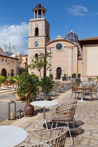 a building with a clock tower and tables and chairs at The Level at Meliá Villaitana in Benidorm