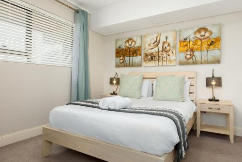 a bedroom with a large white bed and a window at Waters Edge Apartments in Cape Town