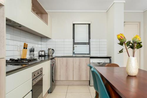 a kitchen with a wooden table with a vase of flowers at Waters Edge Apartments in Cape Town