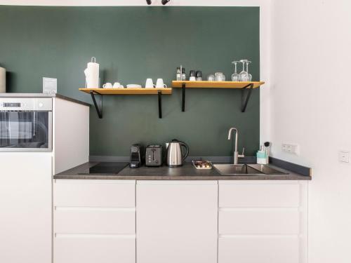 a kitchen with white cabinets and a sink at Limehome Aachen Vereinsstraße in Aachen