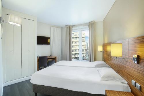 伊西萊穆利諾的住宿－Hotel Gabriel Issy Paris，一间设有大床和窗户的酒店客房
