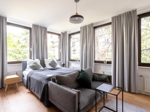 a bedroom with a bed and a couch and windows at Limehome Aachen Vereinsstraße in Aachen