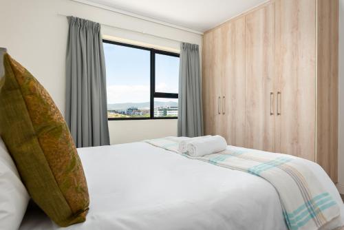 a bedroom with a large white bed with a window at Waters Edge Apartments in Cape Town