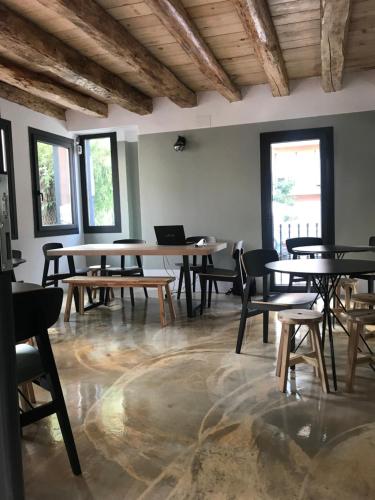 an empty room with tables and chairs and windows at Albergue de Pas in El Pont de Suert